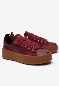 Sneaker bordeaux con tomaia in tessuto testurizzato, punta rotonda e suola in gomma piattaforma. Presenta occhielli dorati e un dettaglio del logo sul lato.