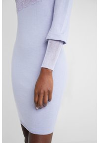 Abito in maglia lavanda fitted con maniche lunghe, caratterizzato da un polsino testurizzato e dettagli in pizzo. Tessuto morbido e lunghezza fino a metà coscia.