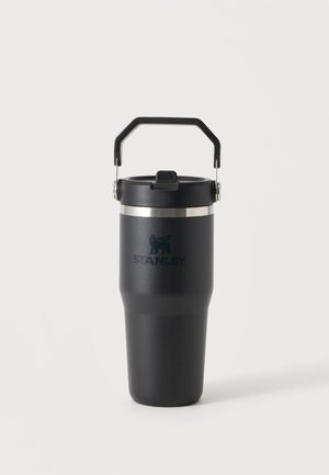 Vaso de viaje aislado negro con asa y tapa abatible, con banda plateada y logo de Stanley en el cuerpo.