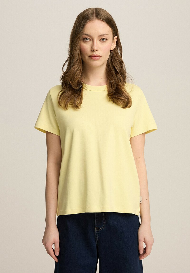 Żółta bawełniana koszulka z okrągłym dekoltem, krótkimi rękawami i luźnym krojem. Charakteryzuje się gładką fakturą i minimalistycznym designem.