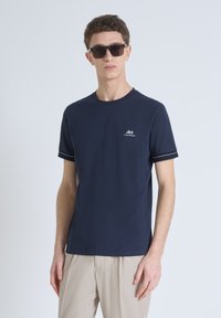 T-shirt blu navy a maniche corte in cotone, con un piccolo logo bianco sul petto e rifiniture a contrasto sulle maniche.