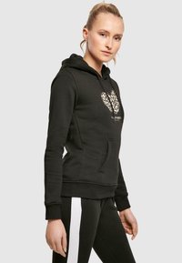 Black hoodie made of cotton blend with a kangaroo pocket and drawstring hood. Features a heart design with a leopard print pattern.