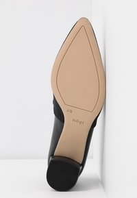 Chaussure noire à bout pointu avec semelle beige lisse, talon carré bas, taille 4½, et le nom de la marque "högl" sur la semelle.