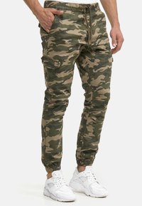 Camouflage cargobroek in groen en beige, voorzien van een elastische tailleband, trekkoord, zijzakken en aansluitende manchetten.