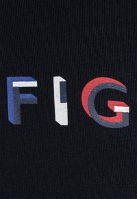 Tessuto nero con lettere in grassetto e multicolore che formano la parola "FIG" in varie texture: blu, bianco e rosso su uno sfondo liscio.