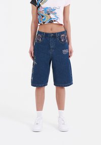 Pantalones cortos de mezclilla de corte relajado, con bordado floral en los bolsillos y los lados, de color azul oscuro y con dobladillo deshilachado.