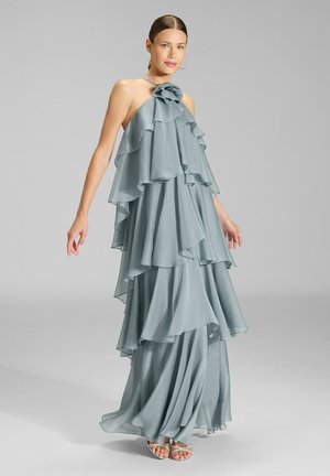 Flowy, layered halter dress in soft blue fabric. Features ruffles at the neckline, cascading tiers, and a long, flowing silhouette.
