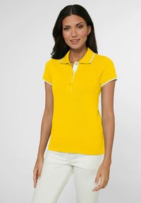 Geel poloshirt met een witte kraag en mouwboorden, met een klassieke pasvorm en een zachte textuur. Draag het met lichtgekleurde broeken.