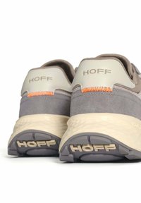 Une paire de baskets Hoff grises et beiges vue de l'arrière, montrant des semelles beiges texturées et des détails de couture orange.