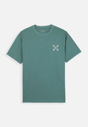 T-shirt en coton teal avec un col rond. Présente un motif floral en blanc et jaune sur la poitrine gauche. Manches courtes, coupe décontractée.