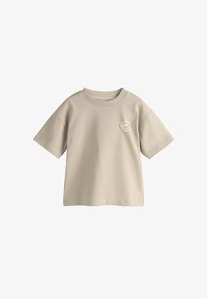 Beige bomulds-T-shirt med korte ærmer, rund hals og et lille rundt logo i lys grå på venstre brystområde. Glat tekstur.