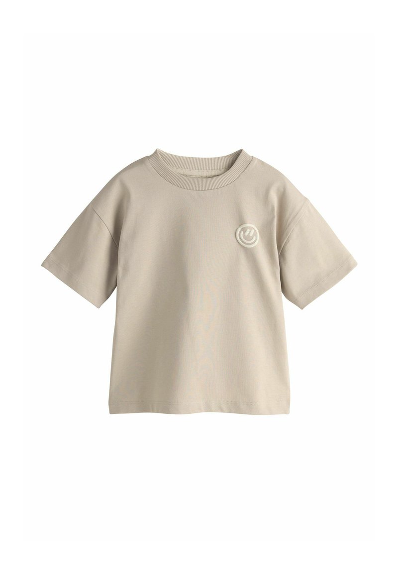 Beiges Baumwoll-T-Shirt mit kurzen Ärmeln, rundem Ausschnitt und einem kleinen runden Logo in Hellgrau auf der linken Brustseite. Glatte Textur.