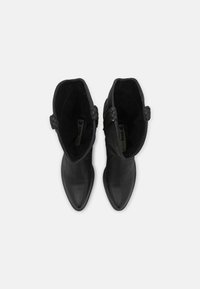 Czarne botki za kostkę z ostrymi noskami, wykonane z gładkiej skóry. Posiadają plecione detale po bokach oraz miękką podszewkę wewnętrzną.