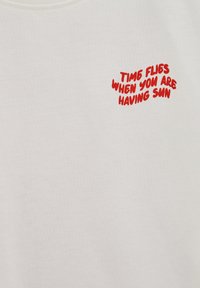 Biely textil s červeným textom "ČAS LETÍ, KEĎ SA SLNÍŠ" v hravom, nepravidelnom písme.