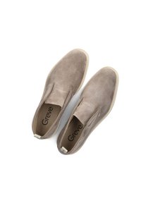 Braune Wildleder Slipper mit Nubuk-Oberfläche, elastischen seitlichen Einsätzen und off-white Gummisohlen. Markenname 'Greve' innen eingeprägt.