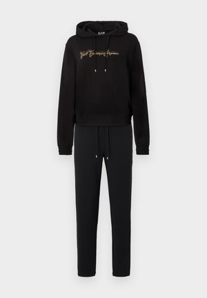Schwarzer Hoodie mit goldenen Aufdrucken und Kordeln, kombiniert mit passenden schwarzen Jogginghosen. Beide aus weichem Stoff gefertigt, mit gerippten Bündchen und Bund.