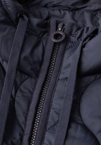 Giubbotto trapuntato blu navy con chiusura a zip, caratterizzato da una superficie texturizzata, cordini regolabili e un design con scollatura arrotondata.