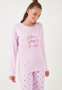 Ibolyaszínű pizsama szett hosszú ujjú felsővel, amelyen a "DONUT WORRY BE HAPPY" felirat látható, és rózsaszín pöttyök a hozzá illő nadrágon. Puha anyag, laza szabás.