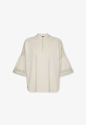 Beige bluse med nøglehulsudskæring, flagrende ærmer og blonde detaljer langs skuldre og ærmekanter.