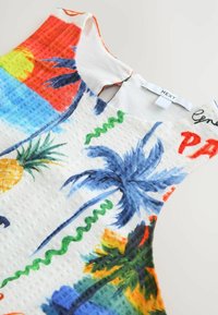 Top de tirantes colorido que presenta una tela texturizada con un patrón tropical, que incluye piñas y palmeras en tonos vibrantes.
