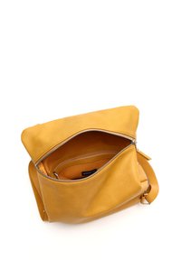 Žltá kožená taška so zipsovým uzáverom. Má jeden ramenný popruh, mäkkú textúru a priestranný interiér s jemnou podšívkou.