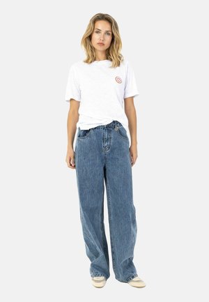 Hvid bomuld t-shirt med et lyserødt smiley-mærke, kombineret med løse blå denimjeans med lys vask og frynset kant.