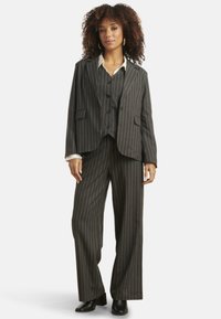 Gray pinstripe suit featuring a fitted blazer with two pockets and a three-button closure, paired with wide-legged trousers and a white shirt.