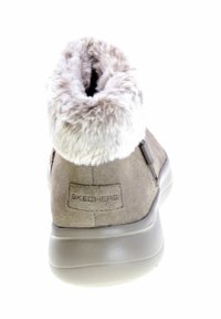 Stivale alla caviglia in suede grigio con colletto in pelliccia sintetica grigia chiara e soffice, presenta una suola in gomma e una toppa con logo sul retro.