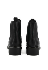 Stivaletti neri alla caviglia con texture in pelle liscia, pannelli elastici laterali e tacco basso a blocco. Vista posteriore che mette in evidenza le cuciture e la forma della scarpa.