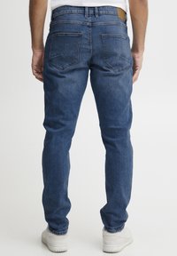 Jeans de denim de corte slim en azul oscuro con una textura suave, diseño de cinco bolsillos y parche de cuero en la cinturilla trasera.