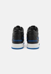 Črne superge s visokim dizajnom, ki vsebujejo modro Reebok oznako, gladko teksturo, belo srednjo sol, ter modre detajle na podplatu.