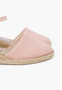 Roze canvas espadrille met een ronde neus, platte geweven jute zool en enkelbanddetails. Gladde textuur met gestikte accenten.