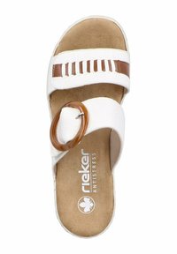 Sandale blanche avec des accents marron, dotée d'une boucle circulaire, d'un design découpé et d'une semelle intérieure texturée portant l'inscription "rieker ANTISTRESS."