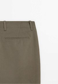 Dos de pantalon vert olive avec deux passants de ceinture et une seule poche passepoilée horizontale sous la ceinture.