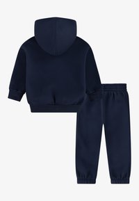 Navy blue two-piece outfit featuring a hooded sweatshirt and tapered sweatpants, both made of soft fabric with ribbed cuffs and waistband.