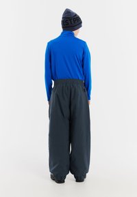 Blå långärmad tröja i kombination med löst sittande, mörkgrå byxor. Byxorna har ett elastiskt midjeband och muddar, lämpliga för kallt väder.