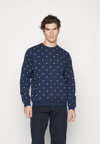 Navy blue sweatshirt with small white logos, crew neckline, ribbed cuffs and hem, made of textured cotton blend fabric.