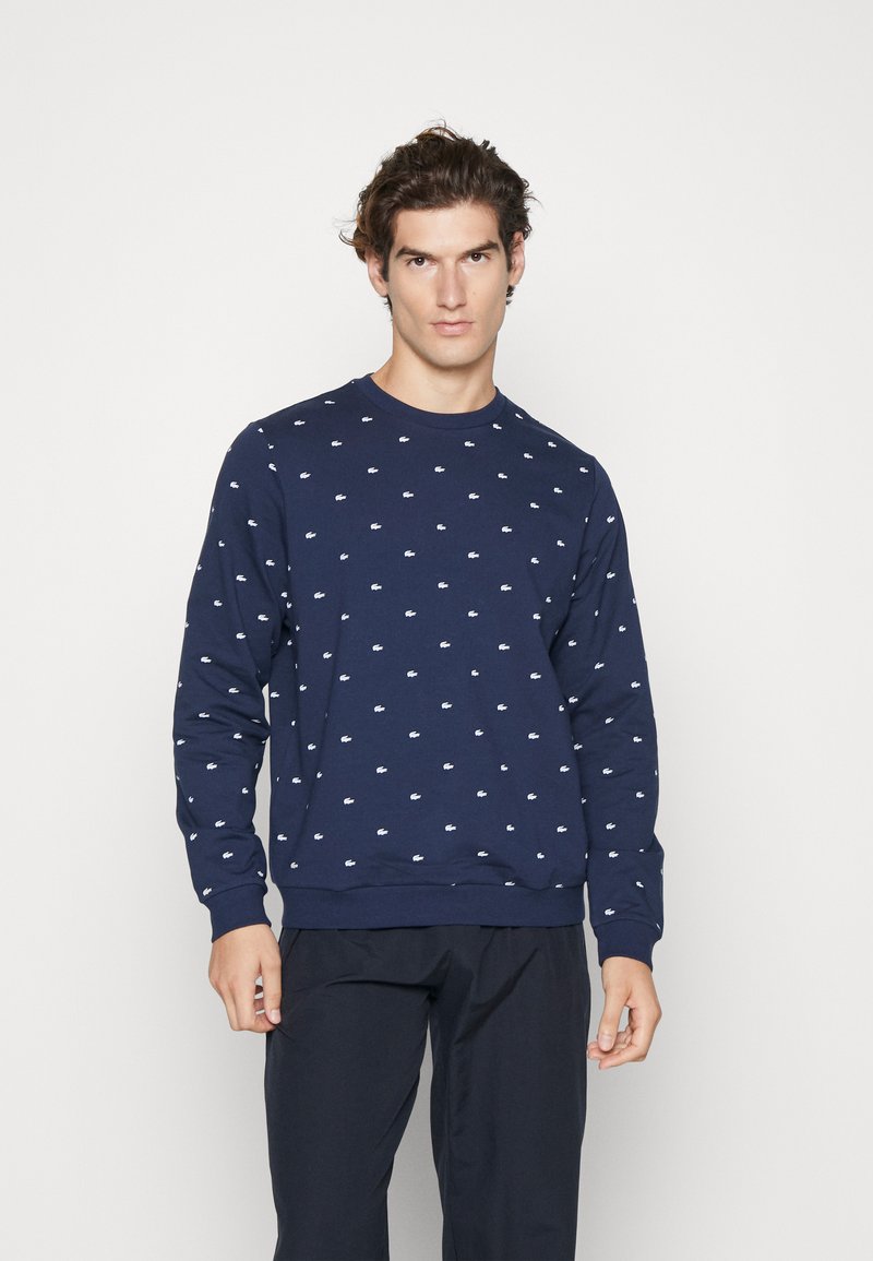 Navy blue sweatshirt with small white logos, crew neckline, ribbed cuffs and hem, made of textured cotton blend fabric.