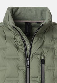 Zielona pikowana kurtka z wysokim kołnierzem, z przodu z zamkami błyskawicznymi oraz siateczkową podszewką. Posiada dwie kieszenie na zamek błyskawiczny oraz metkę z logo wewnątrz.