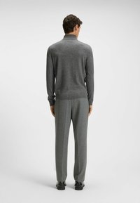 Szary sweter dzianinowy z wysokim kołnierzem, w połączeniu z dopasowanymi szarymi spodniami. Gładka faktura, ribbowe mankiety i detale paska. Czarne buty.