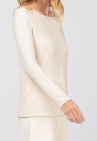 Beżowa bluzka z długim rękawem wykonana z miękkiej tkaniny, z okrągłym dekoltem i dopasowanym krojem, o gładkiej fakturze i minimalnym przeszyciu.