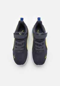 Sneaker in rete grigio scuro con dettagli gialli, superficie testurizzata e cinturino in velcro. Presenta una suola bianca e un linguetta blu sul tallone.