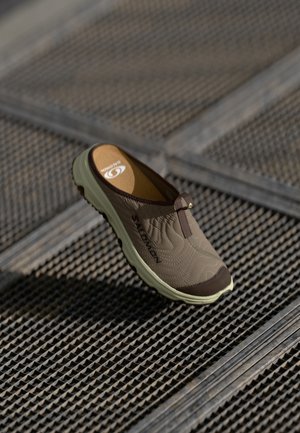 Lichtbruine instapschoen met gestructureerde bovenkant en donkerbruine neus. Lichtgewicht, rubberen zool in lichtgroen met merklogo. Onzichtbaar vetersysteem.