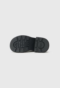 Suela de zapato de goma negra con un patrón de agarre texturizado. Presenta el logotipo circular de "Buffalo" y un tacón ancho y plano para mayor estabilidad.