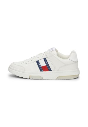 Zapatillas blancas de cuero con acabado texturizado, con rayas horizontales rojas y azules y suela de goma. Diseño minimalista con cierre de cordones.
