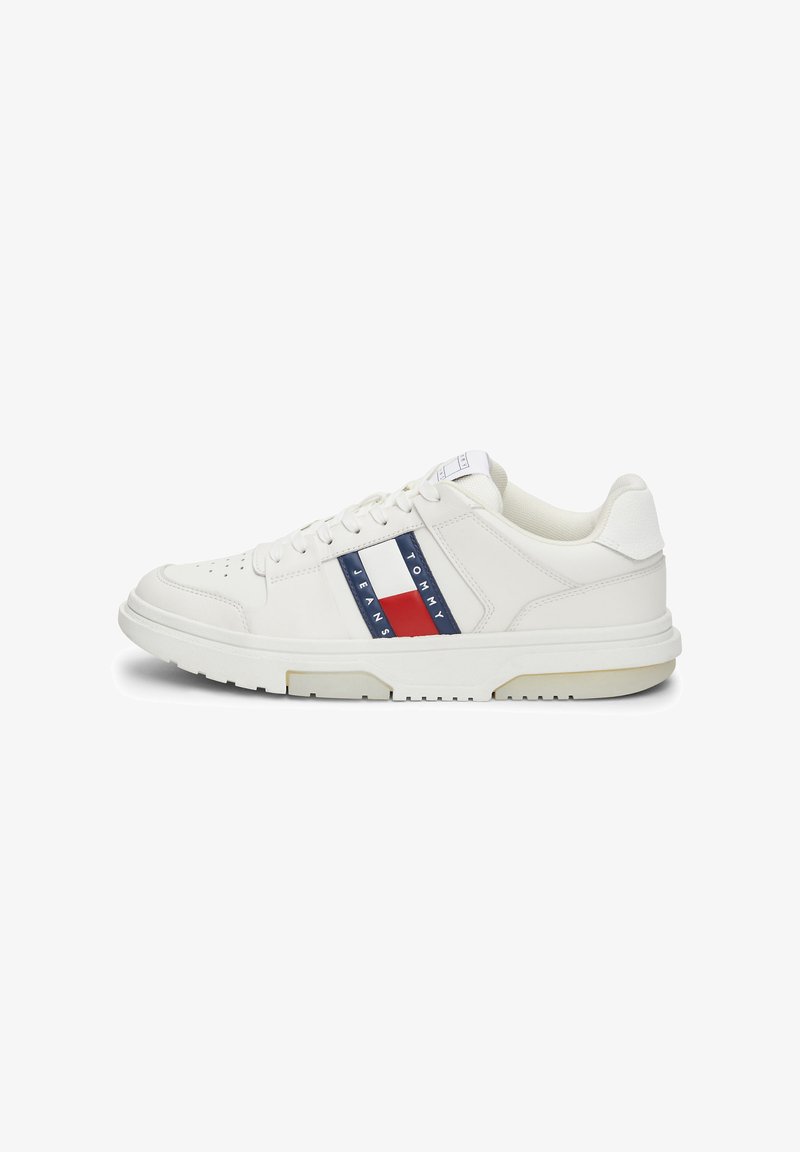 Zapatillas blancas de cuero con acabado texturizado, con rayas horizontales rojas y azules y suela de goma. Diseño minimalista con cierre de cordones.