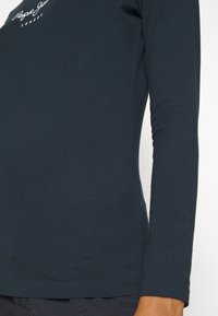 Jūrinės mėlynos spalvos ilgos rankovės marškinėliai, pagaminti iš minkštos medvilnės. Turi apvalų iškirpimą ir mažą baltą "Pepe Jeans London" logotipą ant krūtinės. Lygi tekstūra.
