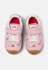 Zapatillas rosas con cordones blancos y una correa de velcro. Material texturizado rosa con patrones de zapatillas de ballet; suela de goma con acentos marrones.