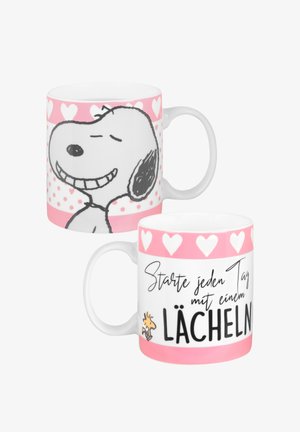 Mug in ceramica con un corpo bianco, accenti a forma di cuore rosa e un'illustrazione di Snoopy nera. Il testo in tedesco recita "Starte jeden Tag mit einem Lächeln."