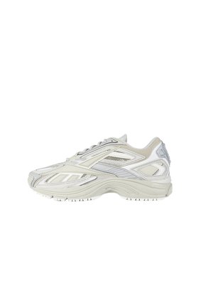 Sneaker atletica grigio chiaro e bianco con pannelli in mesh, sovrapposizioni sintetiche stratificate, chiusura con lacci e suola spessa imbottita mostrata di profilo laterale.